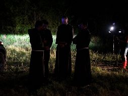Sacerdotes de la Arquidiócesis de San Antonio permanecen en oración cerca del lugar donde se encontró el tráiler con los cuerpos de los migrantes. AFP / S. Flores