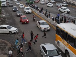 Sin la presencia de agentes viales, los usuarios del transporte público se arriesgan al momento de cruzar hacia la parada del camión que se encuentra en los carriles centrales de la carretera a Chapala, a la altura del Álamo. EL INFORMADOR/A. Camacho