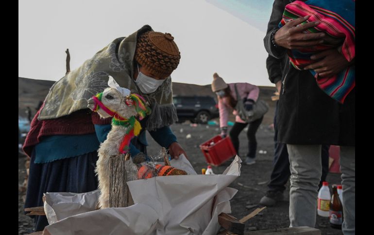 Un chamán lanza chorros de cerveza alrededor de una fogata, en la que arden frutas, dulces, incienso y raíces, para que la Pachamama retribuya con salud y prosperidad a sus devotos. AFP/A. Raldes