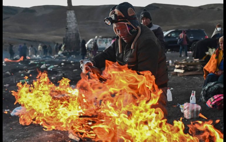 Un chamán lanza chorros de cerveza alrededor de una fogata, en la que arden frutas, dulces, incienso y raíces, para que la Pachamama retribuya con salud y prosperidad a sus devotos. AFP/A. Raldes