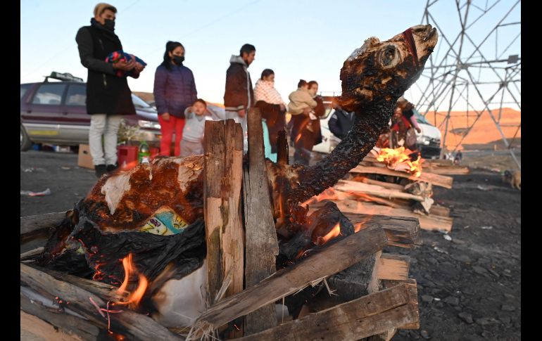 Un chamán lanza chorros de cerveza alrededor de una fogata, en la que arden frutas, dulces, incienso y raíces, para que la Pachamama retribuya con salud y prosperidad a sus devotos. AFP/A. Raldes