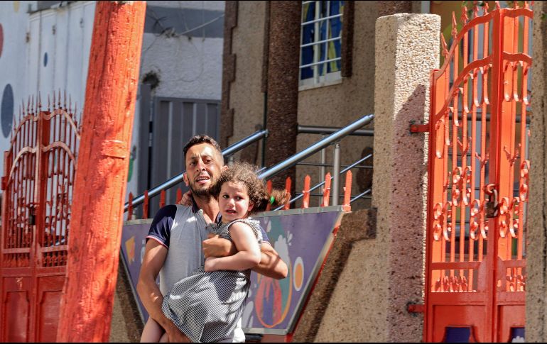 Un hombre palestino carga a su hija después de evacuar su casa durante un ataque aéreo israelí en la ciudad de Gaza, el 7 de agosto de 2022. AFP/M. Abed