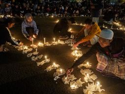 Varias personas encienden velas en honor a las víctimas mortales durante una vigilia. AP/D. Bisinglasi