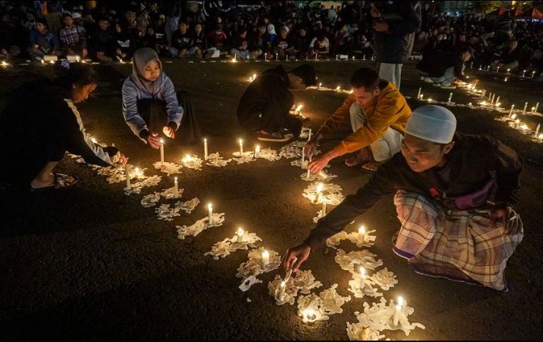 Varias personas encienden velas en honor a las víctimas mortales durante una vigilia. AP/D. Bisinglasi