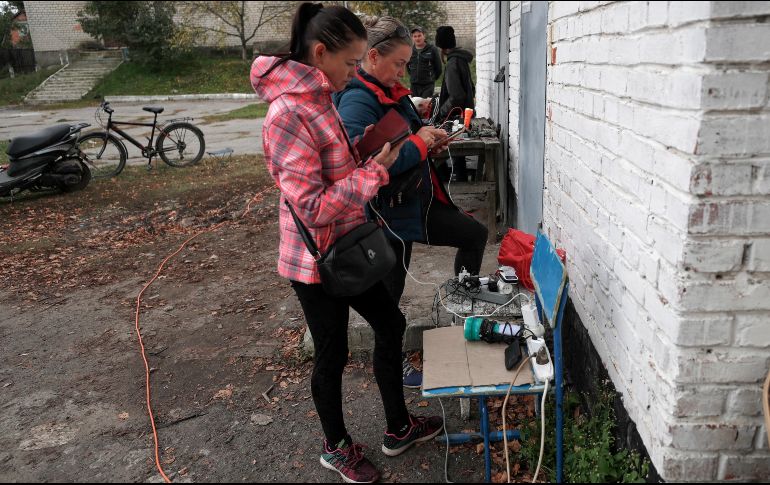 Residentes de Izium afectados por los bombardeos de este lunes recargan sus celulares en una estación móvil instalada por autoridades. EFE/A. Safadi