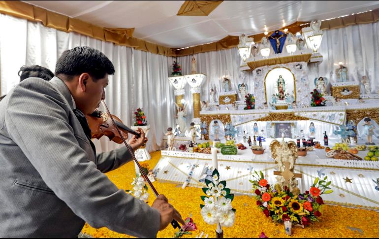 Varias personas visitan altares durante la celebración de Día de Muertos, en el municipio de Huaquechula, Puebla. EFE / H. Ríos
