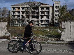 Un hombre con una bicicleta pasa frente a un edificio dañado por los bombardeos en la aldea liberada de Shchurove, región de Donetsk. AP/A. Andriyenko