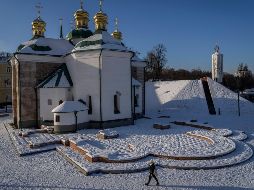 Una mujer pasa frente al patio de una iglesia cubierto de nieve en Kiev, Ucrania. AP/B. Armangue