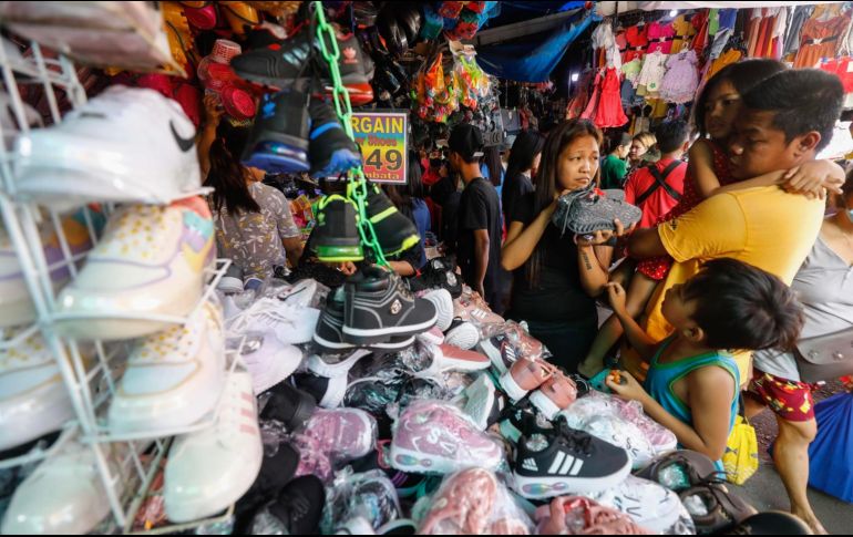 Una familia mira varios zapatos a la venta en un mercado de gangas en Quezon City, Metro Manila, Filipinas. Los filipinos acuden en masa a estos sitios para comprar regalos a precios asequibles para completar su lista navideña de amigos y seres queridos. EFE / R. de la Pena