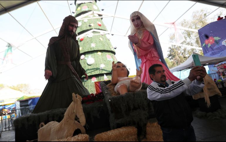 Visitantes se toman fotos junto a un nacimiento gigante realizado por artesanos mexicanos, como parte de las festividades navideñas en la explanada de la alcaldía de Iztapalapa en Ciudad de México. EFE / S. Gutiérrez