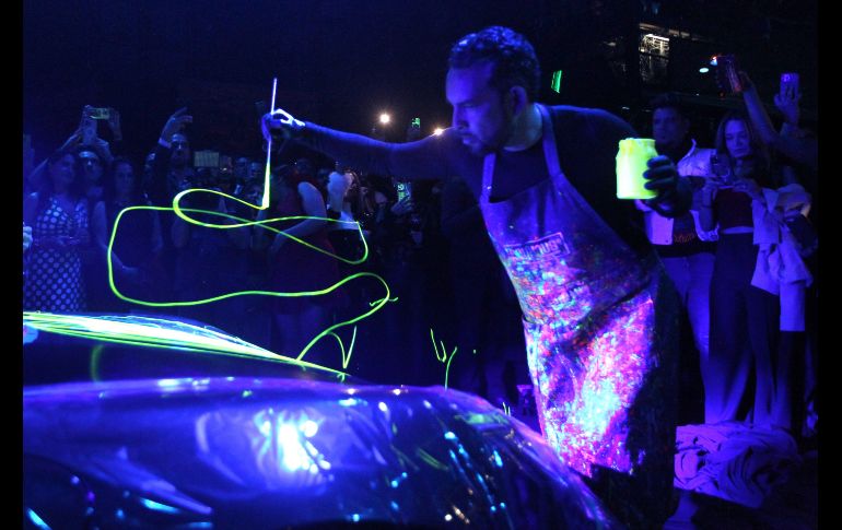 El artista intervino un automóvil de lujo enmarcada la actividad por una atmósfera en destellos neón que provenían de la obra expuesta y además con música de DJ de fondo. EL INFORMADOR / A. Camacho