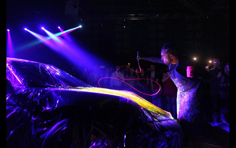El artista intervino un automóvil de lujo enmarcada la actividad por una atmósfera en destellos neón que provenían de la obra expuesta y además con música de DJ de fondo. EL INFORMADOR / A. Camacho