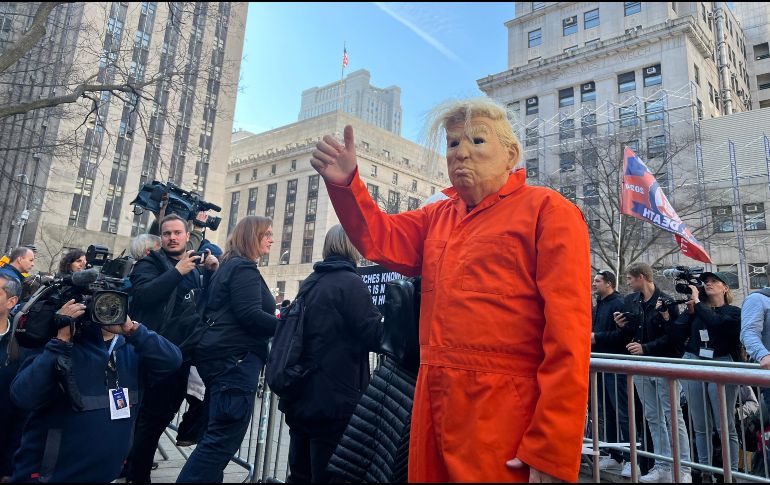 Un hombre, vestido con el uniforme carcelario y una máscara de Trumo, saluda durante la concentración en la plaza Collect Pond Park, aledaña al tribunal donde comparece el expresidente de EU. EFE / S. Yáñez-Richards