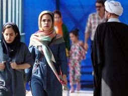 Mujeres iraníes caminan junto a un clérigo en una calle de Teherán en septiembre de 2022. EPA