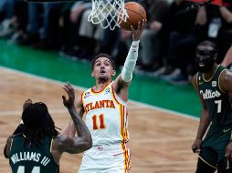 Trae Young esquiva la marca de Robert Williams III y Jaylen Brown. El guardia de Atlanta hizo 38 puntos anoche. AP/C. Krupa