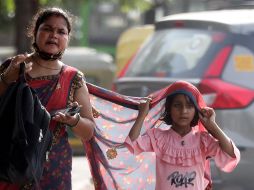 Una niña india se cubre la cabeza con parte de la ropa de su madre durante una ola de calor cerca de Nueva Delhi. EFE/H. Tyagi