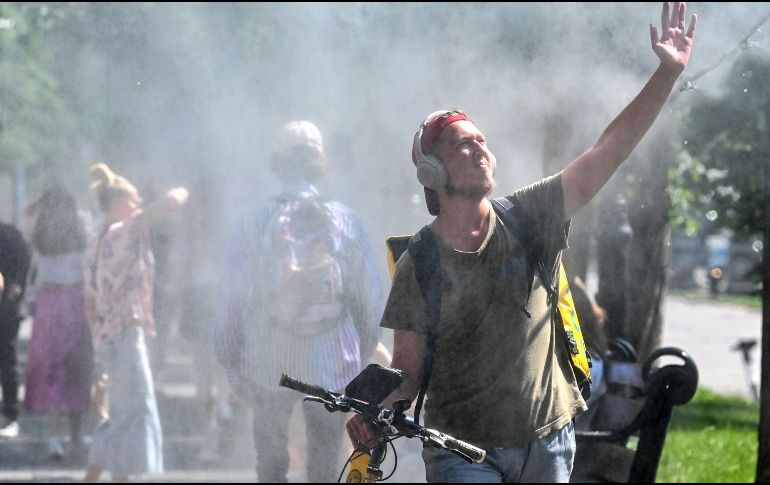Un hombre se refresca mientras pasa junto a un rociador de agua en el centro de Kiev, Ucrania, en el primer día del verano de 2023. AFP / S. Supinsky