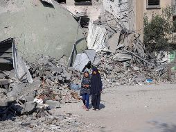 Niñas caminan al lado de edificios destruidos por bombardeos israelíes. XINHUA/R. Abdeljawad