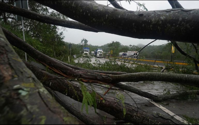 Camiones parados en una carretera bloqueada por los deslizamientos de tierras provocados por 