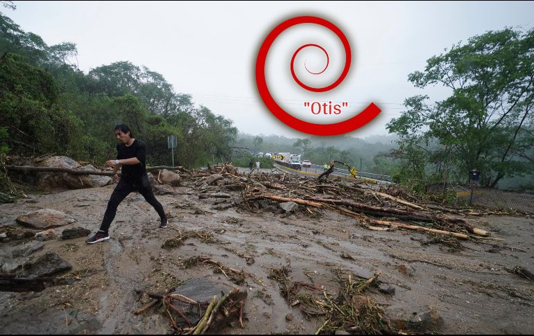 Un hombre cruza una carretera bloqueada por un deslizamiento de tierra provocado por el huracán 