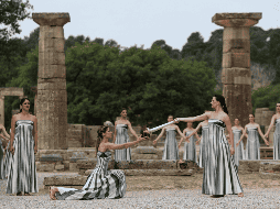 Una actriz vestida como una sacerdotisa griega utiliza el sol para prender una antorcha plateada tras ofrecer una oración simbólica a Apolo, el antiguo dios griego del Sol. EFE / G. Vitsaras