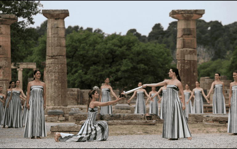 Una actriz vestida como una sacerdotisa griega utiliza el sol para prender una antorcha plateada tras ofrecer una oración simbólica a Apolo, el antiguo dios griego del Sol. EFE / G. Vitsaras