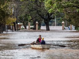 Una mujer acompañada de un niño conduce una embarcación por una calle inundada este lunes en Concordia (Argentina).  EFE/ Ignacio Jesús Rollano