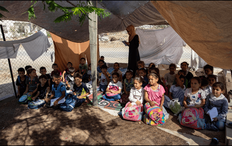 Niños palestinos estudiando en una escuela improvisada, luego de quedarse sin hogar. EFE/H. IMAD