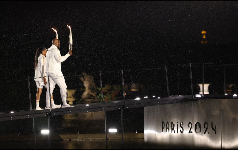 Los atletas galos Marie-Jose Perec (i) y Teddy Riner (d) caminan con la antorcha olímpica momentos antes de encender el pebetero. EFE/ Jan Woitas POOL
