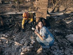 Una vecina sostiene una de las pocas pertenencias que quedaron tras el incendio de su hogar: una taza. AP