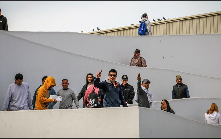 Migrantes deportados saludan en el puerto fronterizo de El Chaparral, este miercoles en Tijuana; mismos que ya permanecían en centros de detención desde la administración del ahora expresidente Joe Biden. EFE/ J. Terríquez