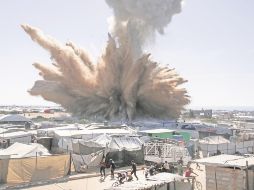 Refugiados palestinos aterrorizados huyen tras el impacto de una bomba en uno de los maltrechos vecindarios al Sur de la Franja de Gaza. AFP