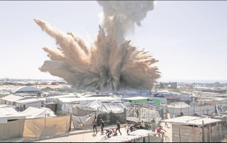 Refugiados palestinos aterrorizados huyen tras el impacto de una bomba en uno de los maltrechos vecindarios al Sur de la Franja de Gaza. AFP