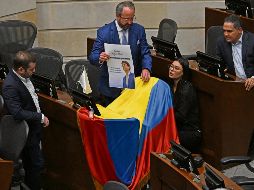 Compañeros de bancada de Miguel Uribe en el Senado colocan una bandera colombiana y un retrato del también candidato en señal de apoyo. AFP