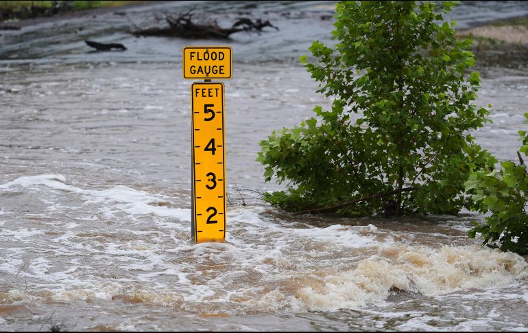 Un medidor de inundaciones marca la altura del agua que fluye sobre un camino que conecta granjas con mercados cerca de Kerrville, Texas. AP