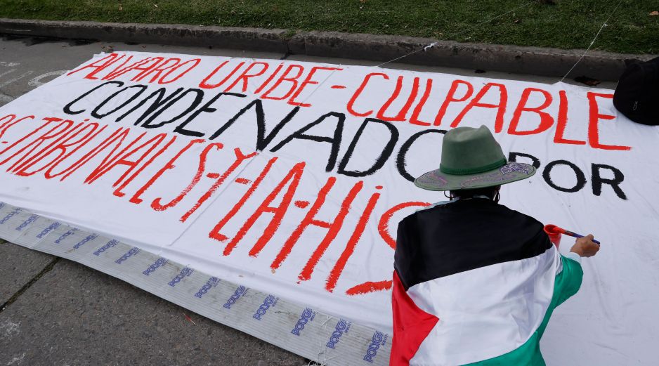Una persona realiza un cartel contra el expresidente Álvaro Uribe este viernes, frente al Complejo Judicial de Paloquemao en Bogotá (Colombia). EFE / M. Dueñas
