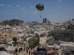 Palestinos en la Ciudad de Gaza corren para recoger ayuda humanitaria lanzada con paracaídas desde el aire. La toma de la capital desplazaría a un millón de personas, muchas de ellas llegadas de otras zonas ya ocupadas. AP/J. Alshrafi
