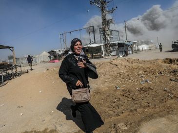Una mujer palestina corre a refugiarse luego de un ataque aéreo israelí ocurrido el lunes. El mes pasado, Israel aprobó un plan para ocupar la Ciudad de Gaza. EFE/M. Saber