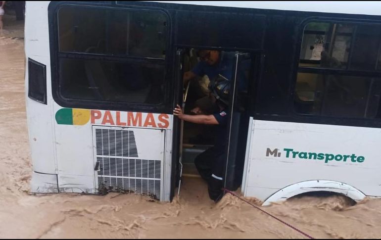 Los pasajeros del camión varado debieron ser auxiliados para evitar ser arrastrados por la corriente. ESPECIAL / Protección Civil y Bomberos de Puerto Vallarta
