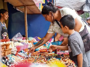 Una mujer y su hijo adquieren artículos para su altar de Día de Muertos, tradición que impulsa la economía local. EL INFORMADOR