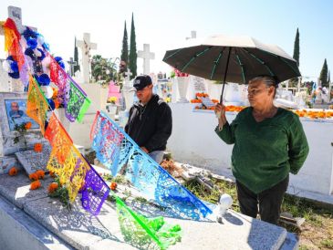 Cerca del mediodía, los pasadizos del Panteón Guadalajara rebosaban con flores de cempasúchil y papel picado. EL INFORMADOR / J. ACOSTA