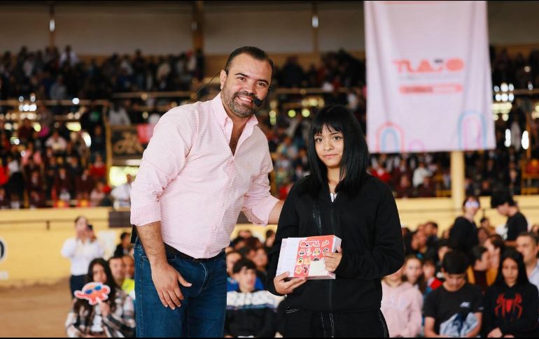 El presidente municipal, Gerardo Quirino Velázquez Chávez, entrega una tableta electrónica a una de las estudiantes destacadas durante el evento en el lienzo charro Santa María. X/GerardoQuirinoV