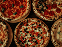 La pizza es un plato italiano, originario de Nápoles; es una base de masa de pan horneada cubierta tradicionalmente con salsa de tomate queso mozzarella y otros ingredientes. CANVA