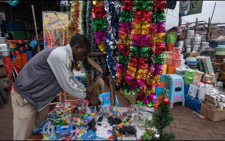 Un vendedor organiza productos y artículos navideños en una concurrida calle comercial de Kampala, Uganda. AFP