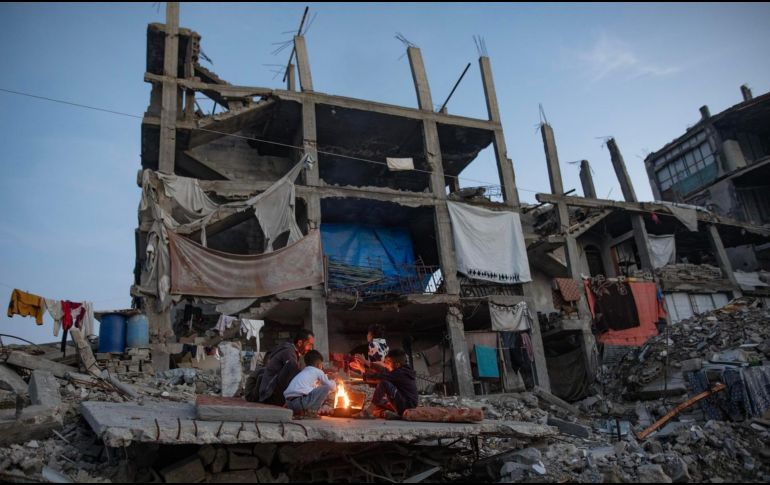 Desplazados palestinos junto a un fuego en los restos de un edificio en Kah Yunis. EFE / EPA / HAITHAM IMAD