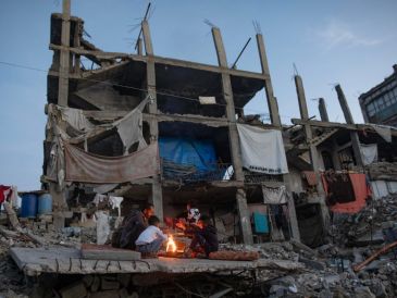 Desplazados palestinos junto a un fuego en los restos de un edificio en Kah Yunis. EFE / EPA / HAITHAM IMAD
