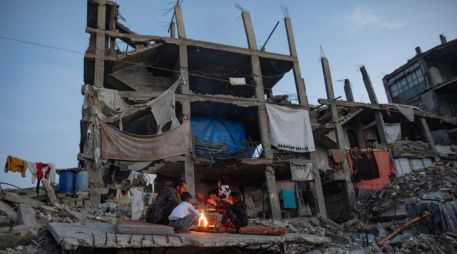 Desplazados palestinos junto a un fuego en los restos de un edificio en Kah Yunis. EFE / EPA / HAITHAM IMAD