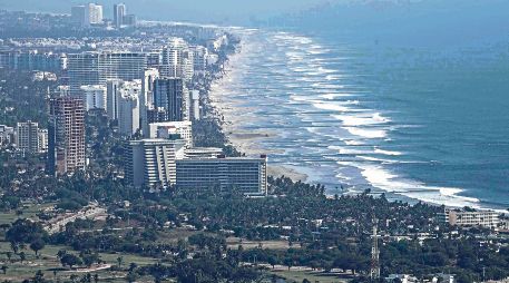 Vista panorámica de una playa en México, donde turistas disfrutan del sol y el mar, reflejando el atractivo natural del país. SUN