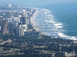Vista panorámica de una playa en México, donde turistas disfrutan del sol y el mar, reflejando el atractivo natural del país. SUN