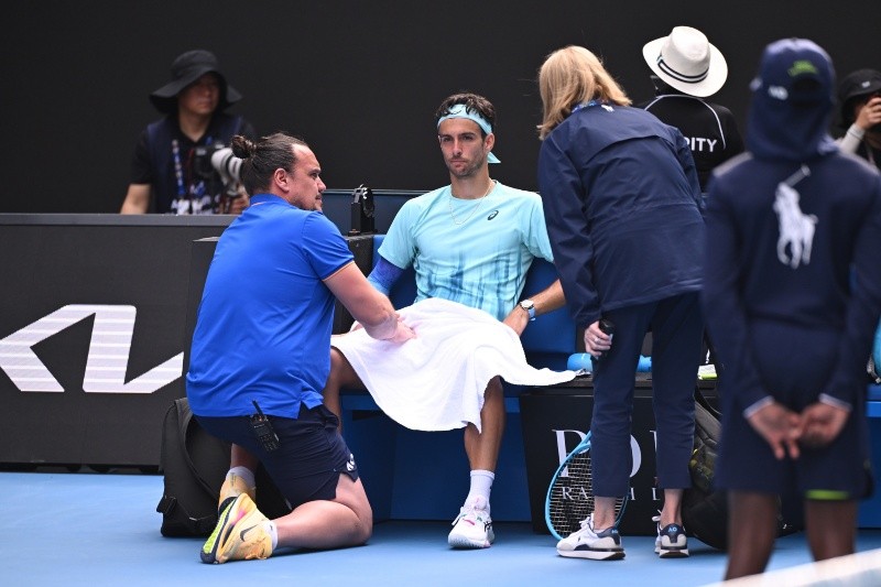 El italiano Lorenzo Musetti (al centro) recibe asistencia médica durante su partido contra Novak Djokovic. EFE / J. Ross
